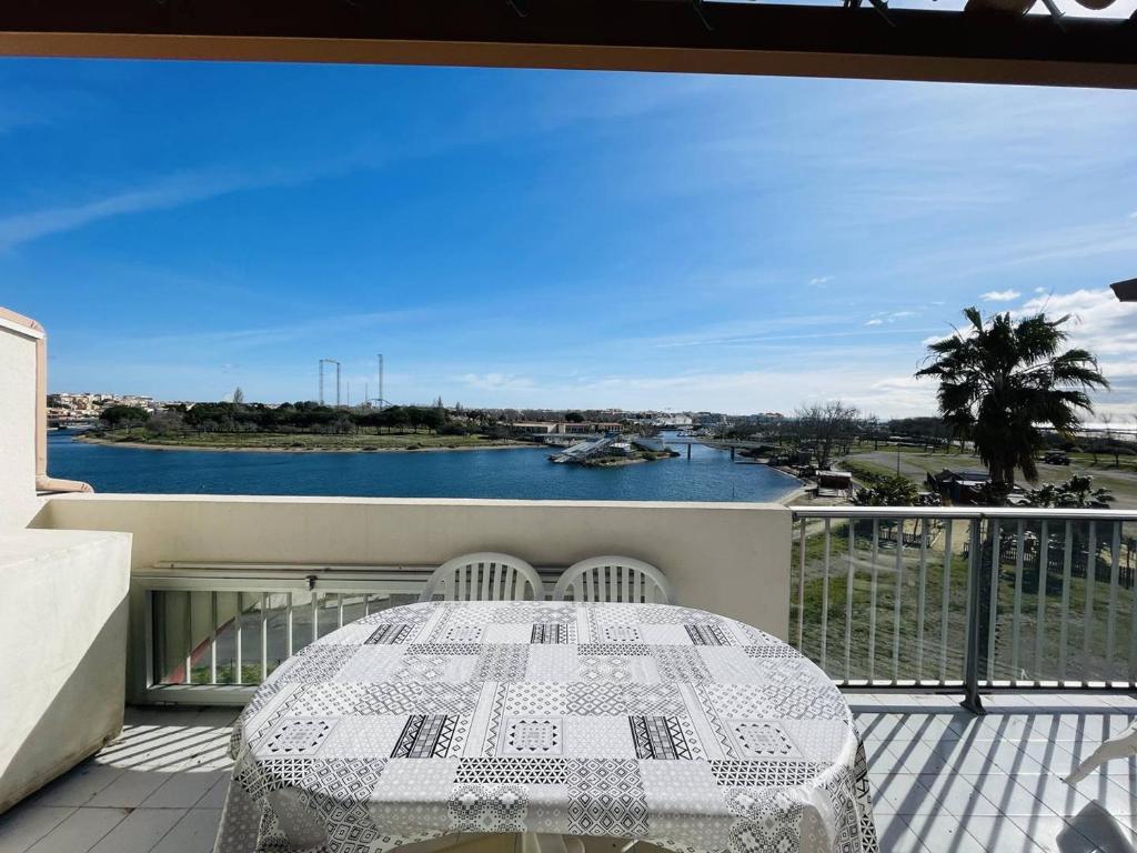 d'un balcon avec une table et une vue sur la rivière. dans l'établissement Appartement proche plage Richelieu avec piscine, clim et parking - FR-1-723-14, au Cap d'Agde