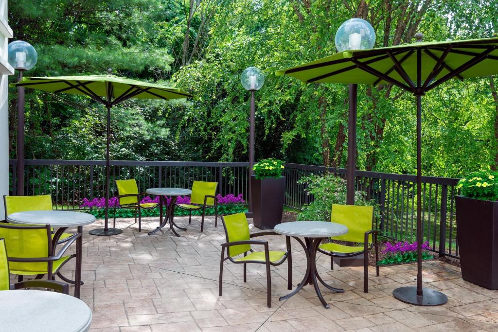 eine Terrasse mit Tischen, Stühlen und Sonnenschirmen in der Unterkunft SpringHill Suites Asheville in Asheville
