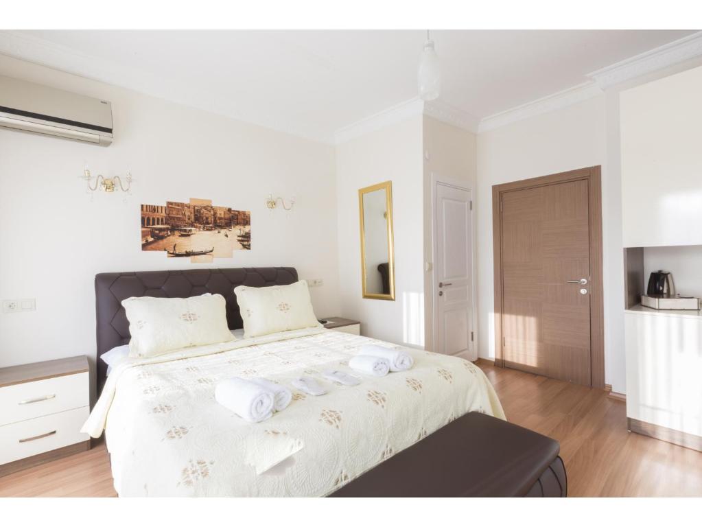 a white bedroom with a large bed with towels on it at Zendy Suite Hotel in Istanbul