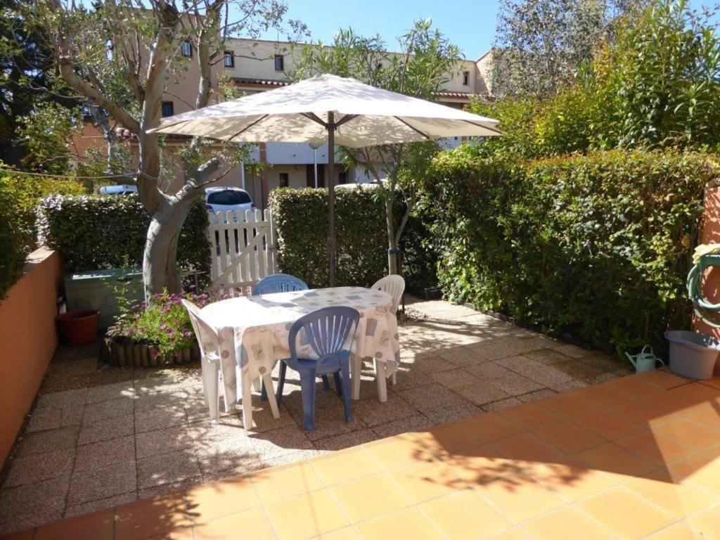 una mesa y sillas bajo una sombrilla en un patio en Appartement Cap d'Agde, 2 pièces, 4 personnes - FR-1-723-83, en Cap d'Agde
