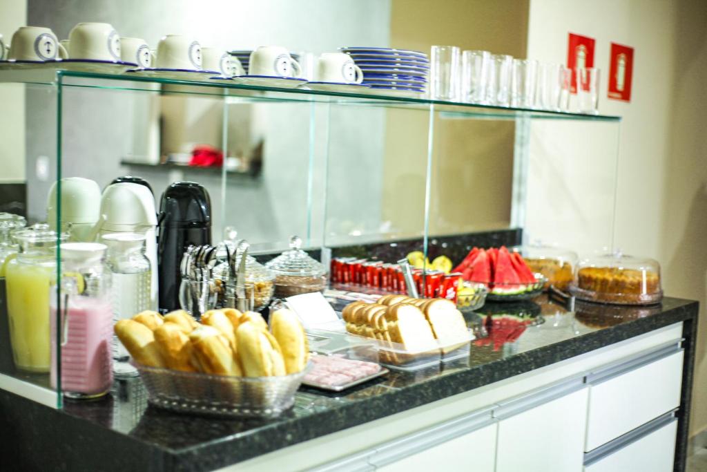 a buffet with plates and bowls of food on a counter at Hotel Tenda Obsession in Sao Paulo