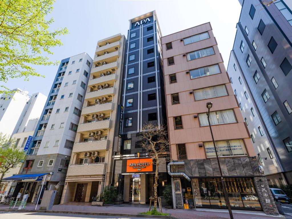 APA Hotel Ginza Shintomicho Ekimae في طوكيو: مجموعة مباني طويلة على شارع المدينة