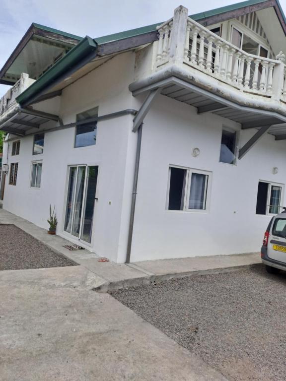 a white house with a balcony on top of it at Laure hébergement in Faaa