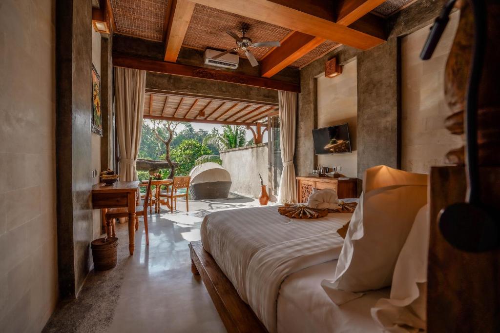 a bedroom with a bed and a table and a fireplace at Kastara Resort in Ubud