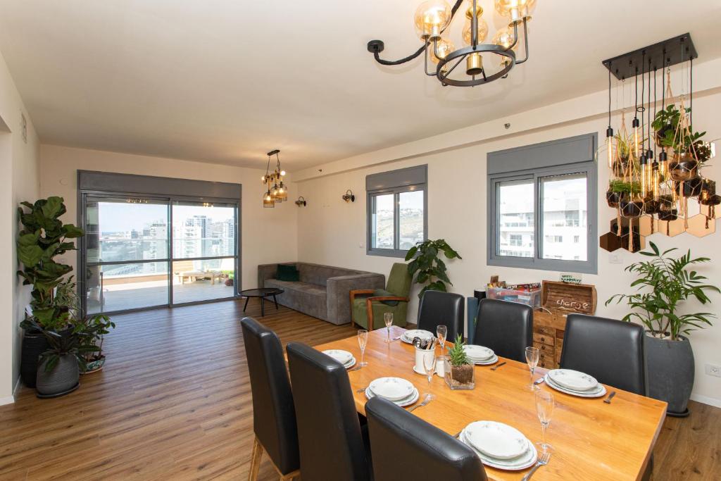 Tirat Carmel Penthouse في Tirat Karmel: غرفة طعام وغرفة معيشة مع طاولة وكراسي