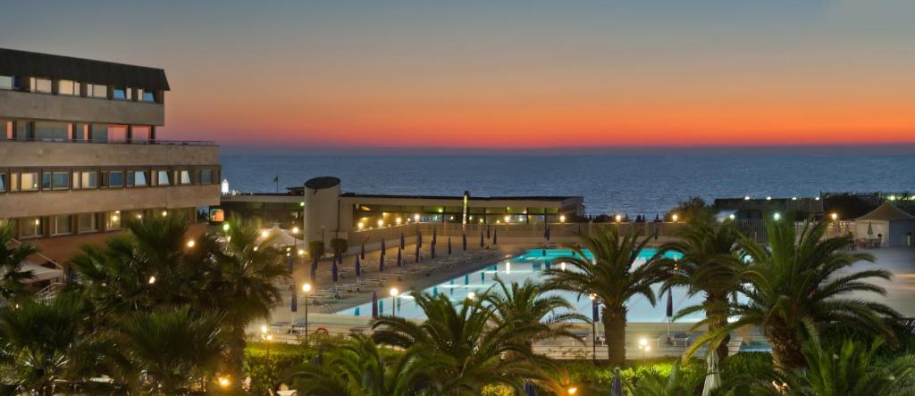 a view of a resort with a pool and the ocean at Grand Hotel Continental in Tirrenia