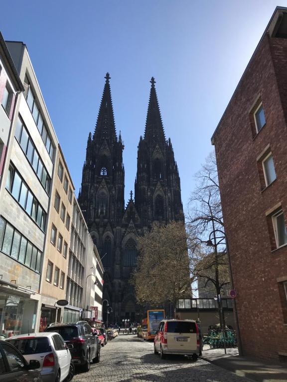 eine Kathedrale mit Autos auf einer Stadtstraße in der Unterkunft City Apartment am Dom in Köln