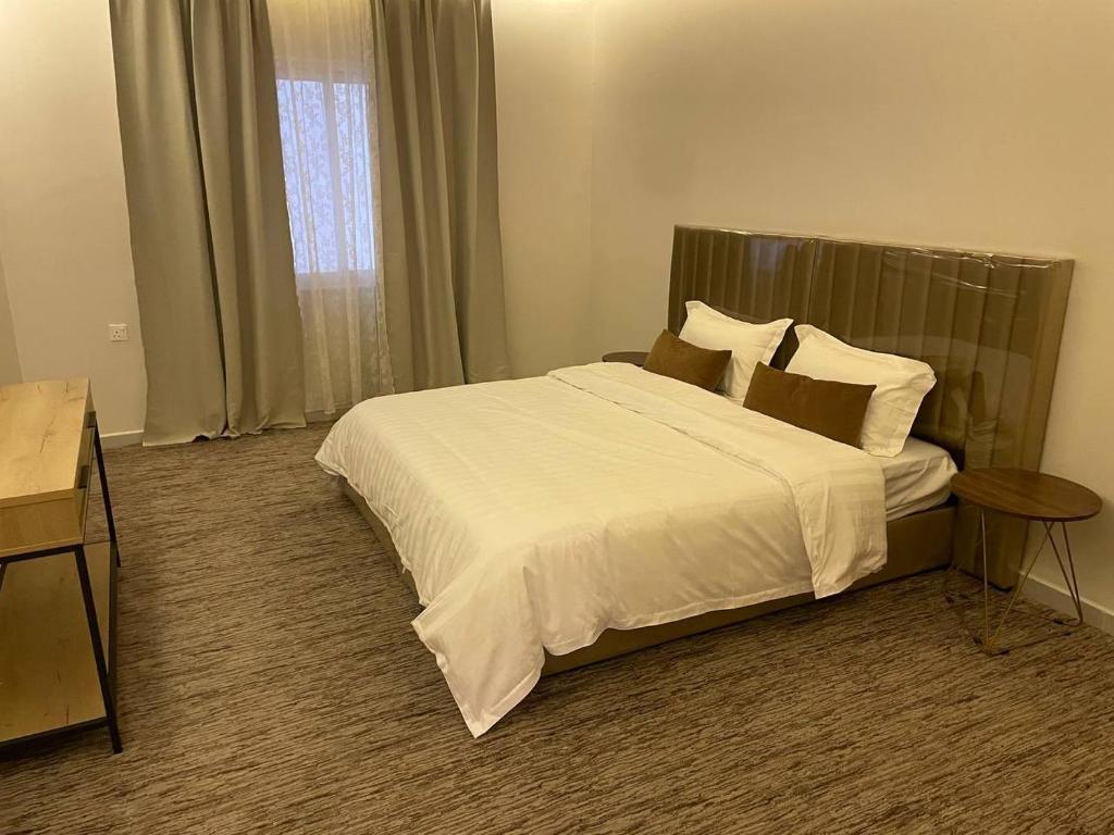 una camera da letto con un grande letto con lenzuola e cuscini bianchi di شاليه الندى a Khamis Mushayt