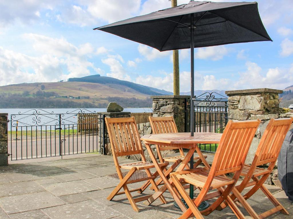 a wooden table and chairs with an umbrella at Castleview West in Lochearnhead