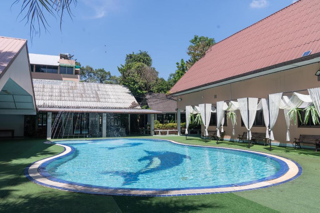 a swimming pool in a yard next to a building at บ้านนารีสอร์ท in Nakhon Nayok