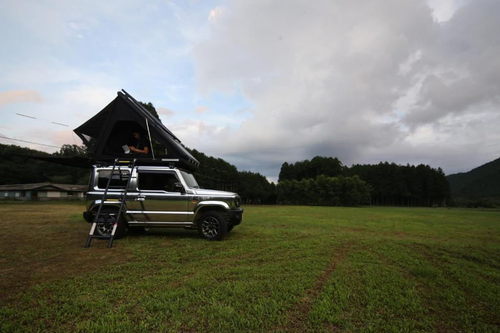 富士宮市にあるFUUUN S Camping Carのトラックの上のテントに座る者