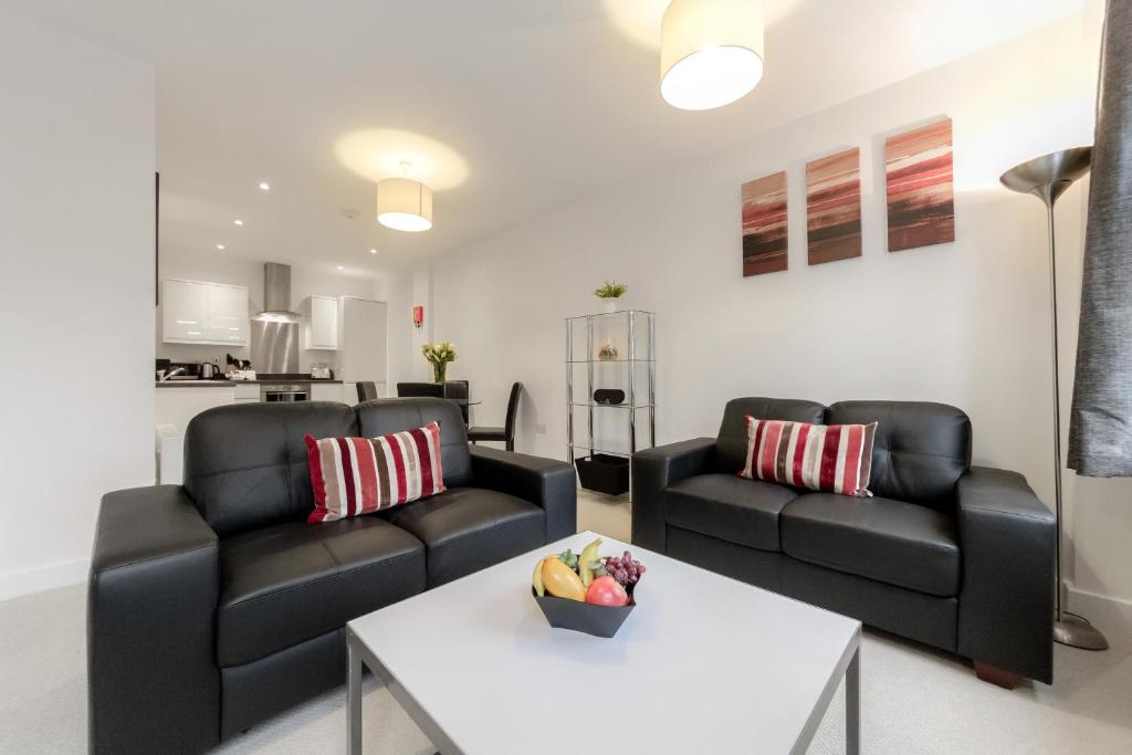 a living room with two black couches and a table at Roomspace Serviced Apartments - Nouvelle House in Sutton