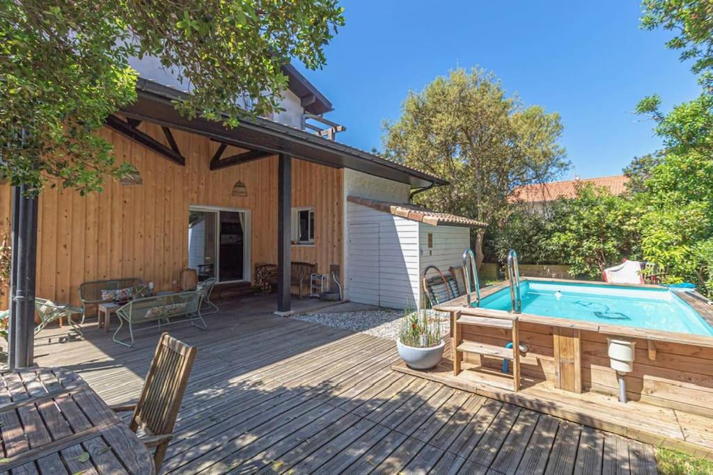 une terrasse avec une piscine et une maison dans l'établissement VILLA TOURTERELLE - A vous la dolce vita, à Soorts-Hossegor