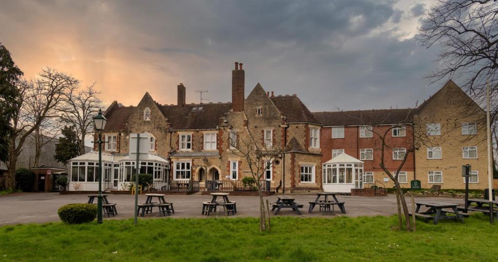 un grupo de mesas de picnic frente a un edificio en Hamlet Hotels Maidstone, en Maidstone