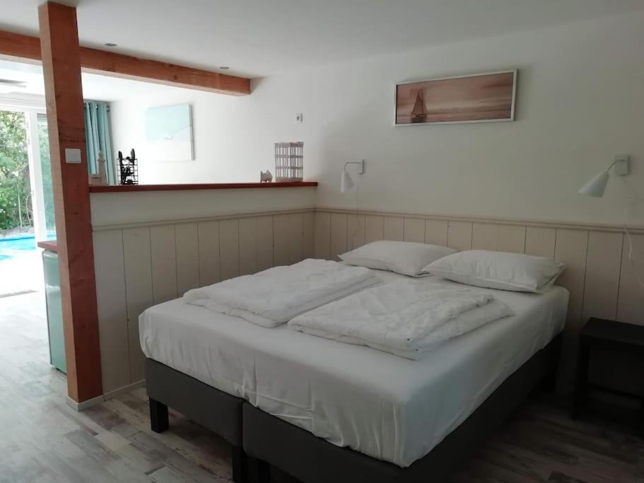 Una cama con sábanas blancas y almohadas en un dormitorio en Strandhuisje DAAN dicht bij zee en strand, en Callantsoog