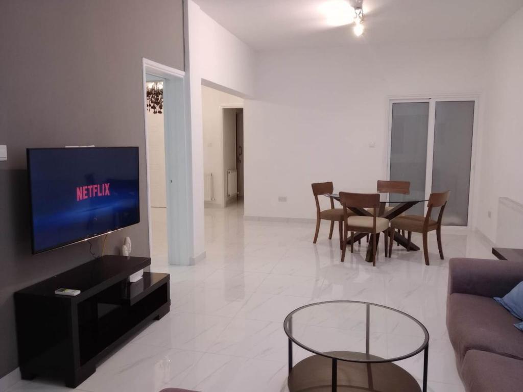 ein Wohnzimmer mit einem Sofa und einem Tisch mit Stühlen in der Unterkunft Zelea Deluxe Apartment (BREAKBOOKING CY) in Limassol