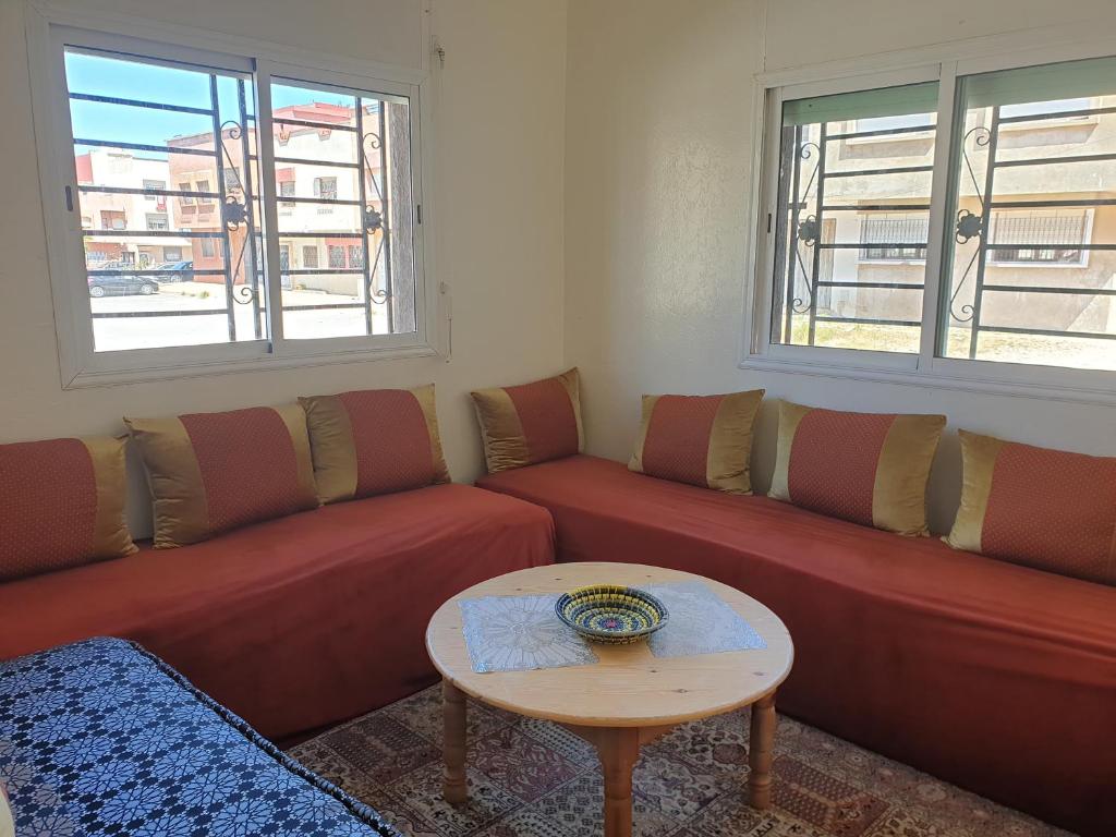 a living room with red couches and a table at Logement a 8mn de mehdia in Kenitra