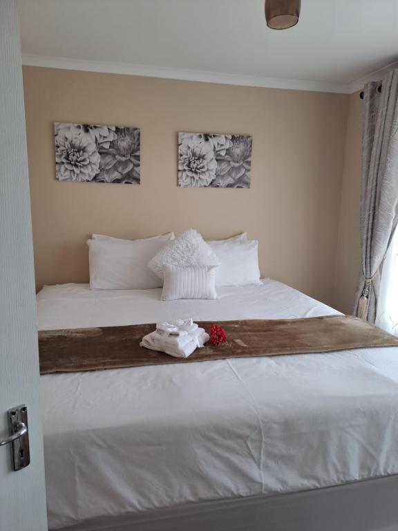 een slaapkamer met een wit bed met bloemen erop bij Elim self catering in Fisherhaven