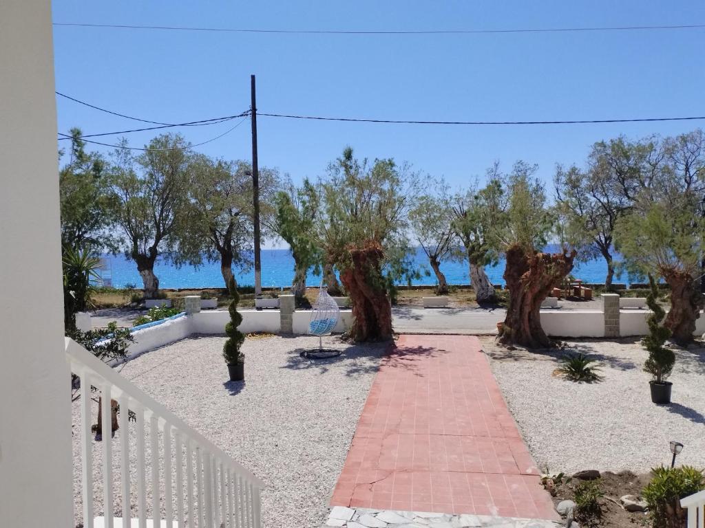 a garden with trees and a white fence at Zorbas in Sougia