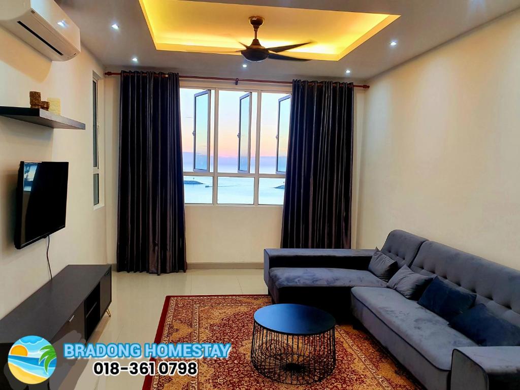 ein Wohnzimmer mit einem blauen Sofa und einem TV in der Unterkunft BRADONG HOMESTAY - MUSLlM ONLY, 3 Queen Bedrooms, Seaview, Infinity Pool, Gym, near Drawbridge & KTCC Mall in Kuala Terengganu