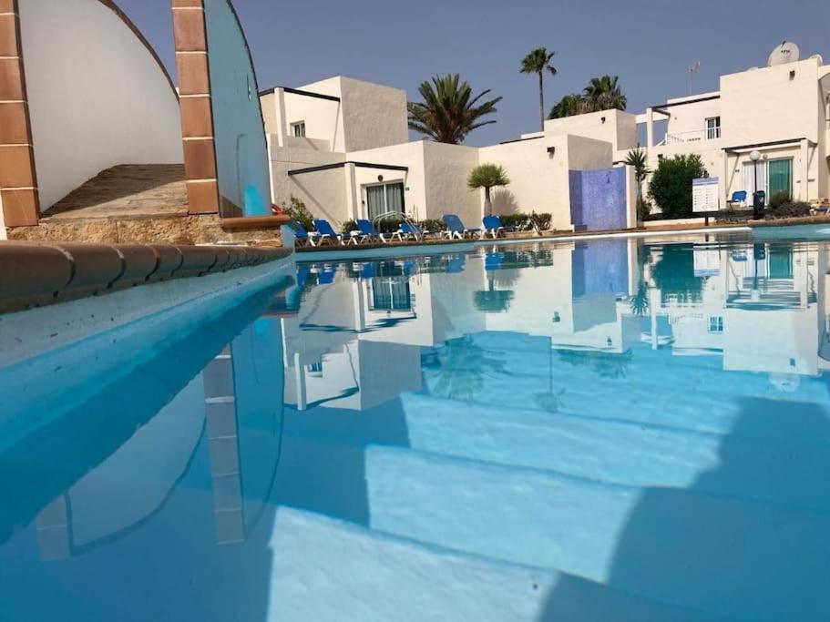 - une piscine d'eau bleue dans un complexe dans l'établissement Corralejo Suite Pool & Gardens - Alisios Playa, à Corralejo