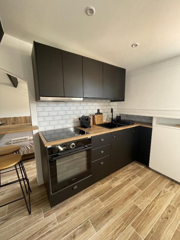 a kitchen with black cabinets and a wooden floor at Villa Corbelle - Grand Studio in Cannes