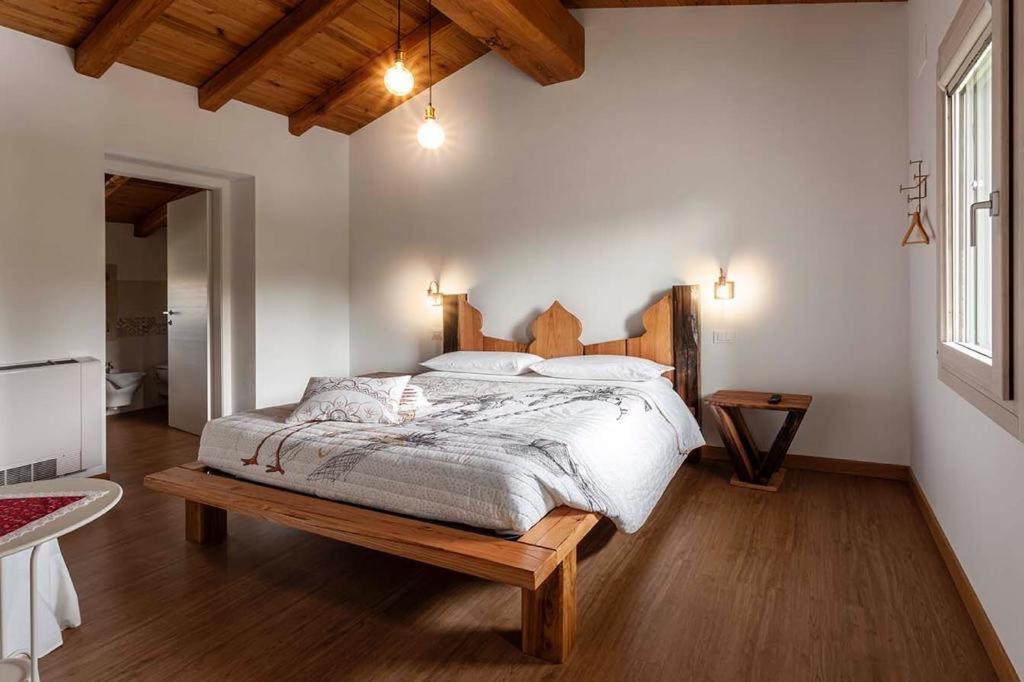 um quarto com uma cama grande e uma cabeceira em madeira em B&b La Casa di Elsa em Polcenigo