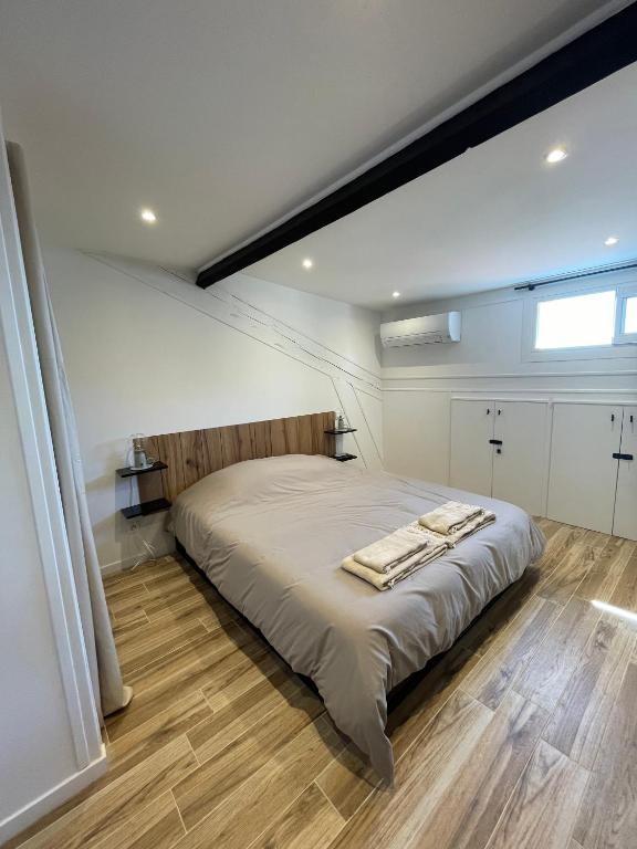 a bedroom with a large bed with a wooden floor at Villa Corbelle - Grand Studio in Cannes
