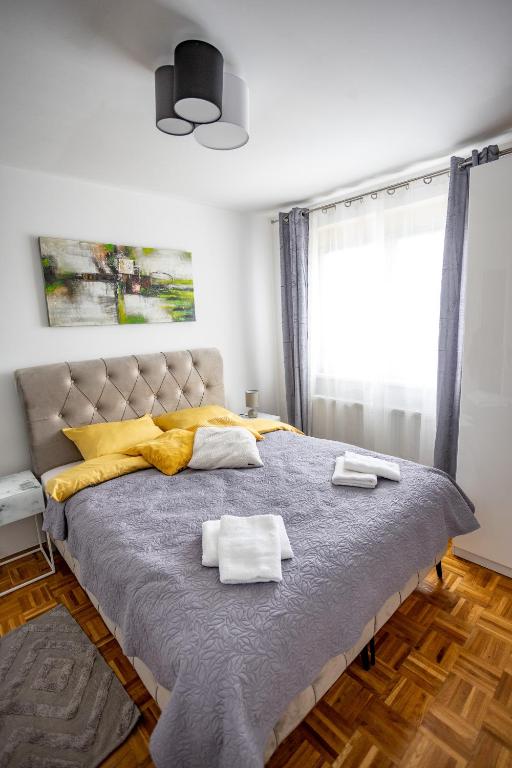 a bedroom with a large bed with two towels on it at Apartman Amal in Vukovar