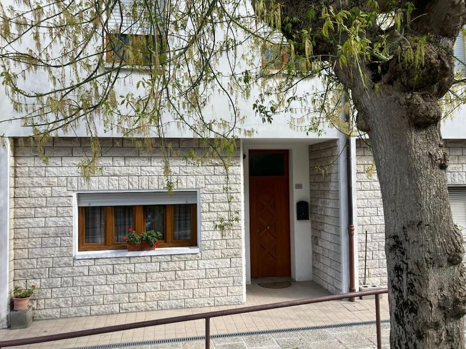 uma casa de tijolos brancos com uma porta vermelha e uma árvore em A casa di Iole em Saludecio