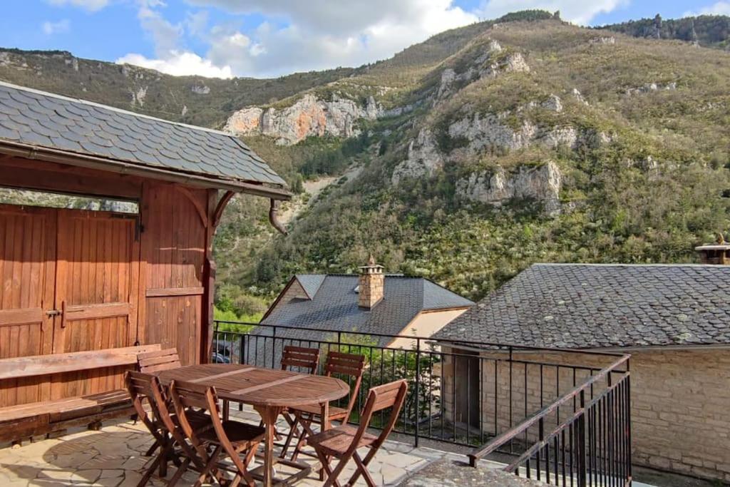 a patio with a table and chairs and a mountain at Gîte de la Batelière in La Malène