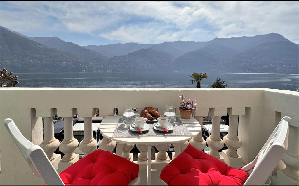 a table on a balcony with a view of the water at Larius Apartment Carate Urio in Laglio