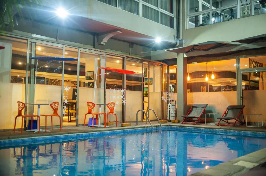 - une piscine avec des chaises, une table et un parasol dans l'établissement Le Grand Mellis Hôtel & Spa, à Antananarivo