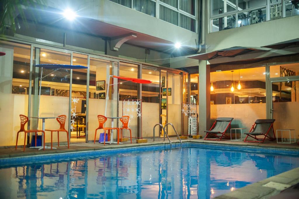 a swimming pool with chairs and a table and an umbrella at Le Grand Mellis Hôtel & Spa in Antananarivo