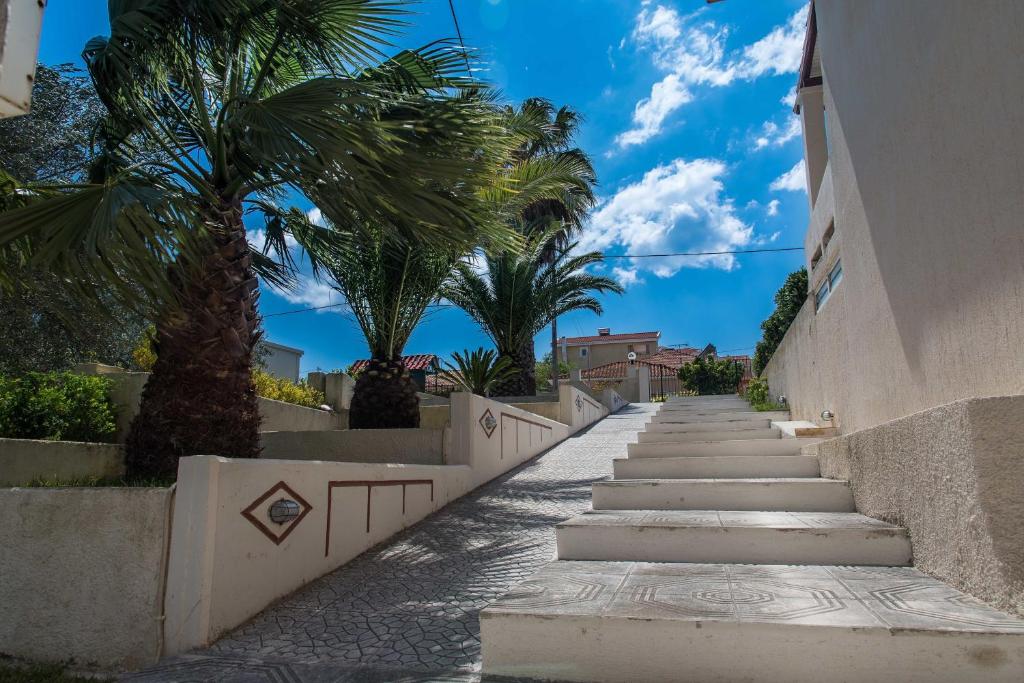 eine Treppe, die zu einem Gebäude mit Palmen führt in der Unterkunft Fokion Studios in Lakíthra