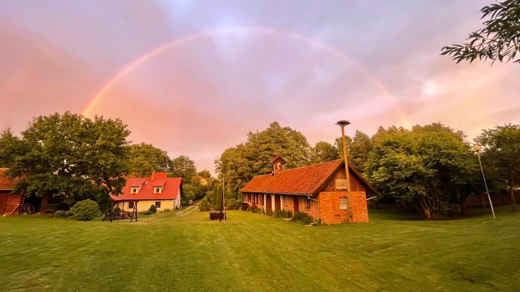 un arco iris en el cielo sobre un granero en Terra Natangia, en Górowo Iławeckie