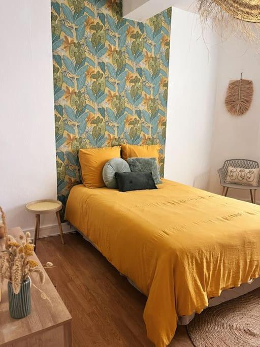 1 dormitorio con 1 cama con colcha amarilla en Appartement chaleureux au centre du village, en Montesquieu-Volvestre