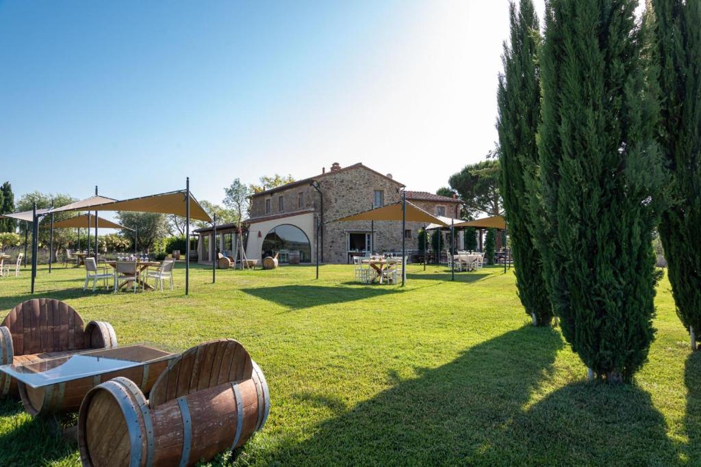 a garden with barrels and a building in the background at Locanda dell'Aioncino in Bibbona