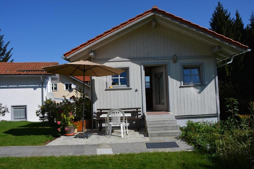 a small house with a table and an umbrella at Holzhaus in Hauzenberg