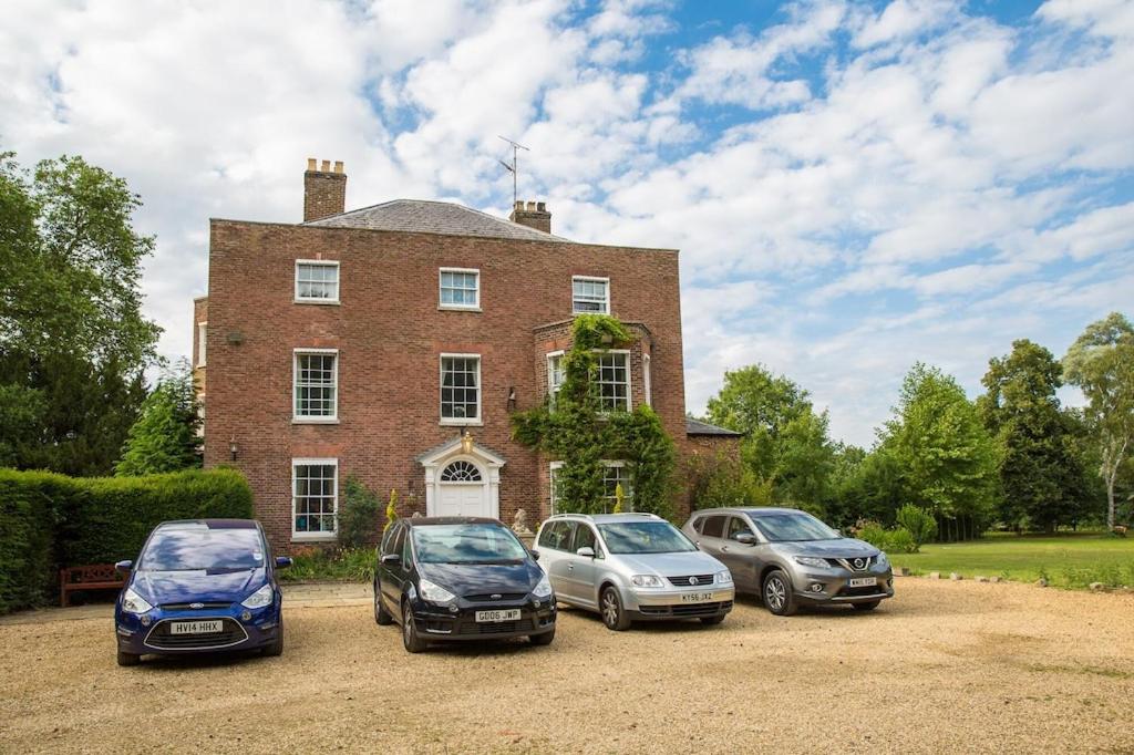 un grupo de tres coches estacionados frente a una casa en The Grange Manor House, Norfolk en Setchey