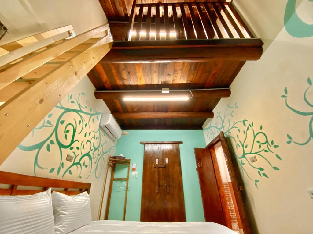 1 dormitorio con 1 cama y escalera de madera en 金門玉宿古厝小包棟民宿 en Jinhu
