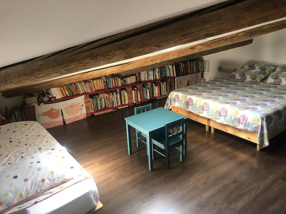 Pokój z dwoma łóżkami, stołem i półkami w obiekcie La Grande Maison Rouge w mieście Mèze