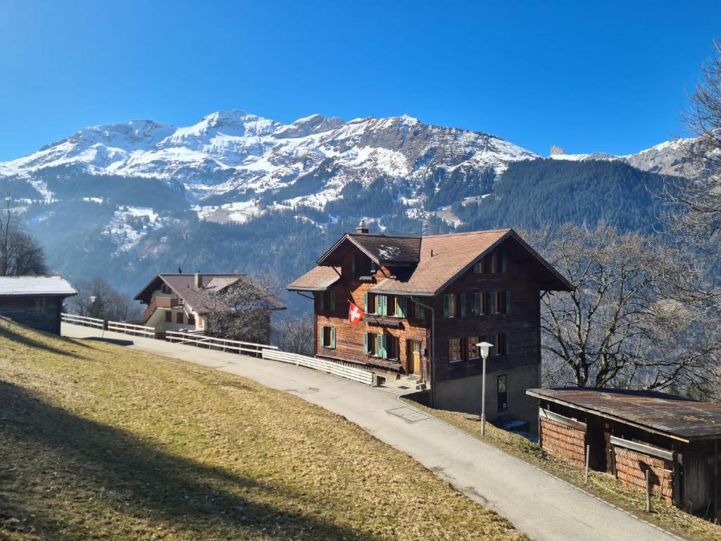 a house on a hill with mountains in the background at Traditional chalet in Wengen - Top Floor in Wengen