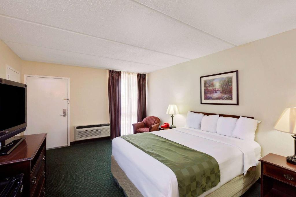 Cette chambre comprend un grand lit et une télévision à écran plat. dans l'établissement Days Inn by Wyndham Bay City, à Bay City