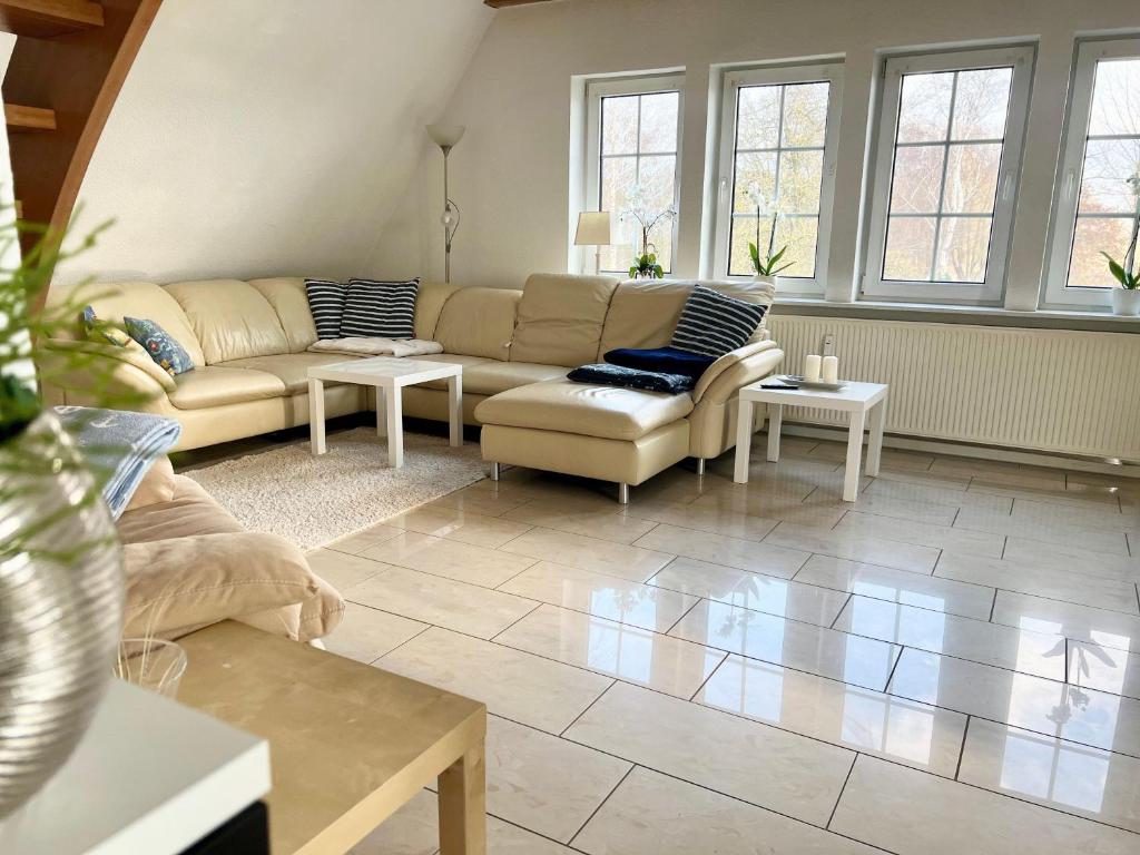 ein Wohnzimmer mit einem Sofa, Tischen und Fenstern in der Unterkunft Seeadler Wohnung in Diedrichshagen