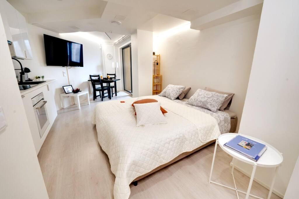 a white bedroom with a bed and a table at Upea yksiö+parveke. Ihastu, parhaalla paikalla. in Tampere