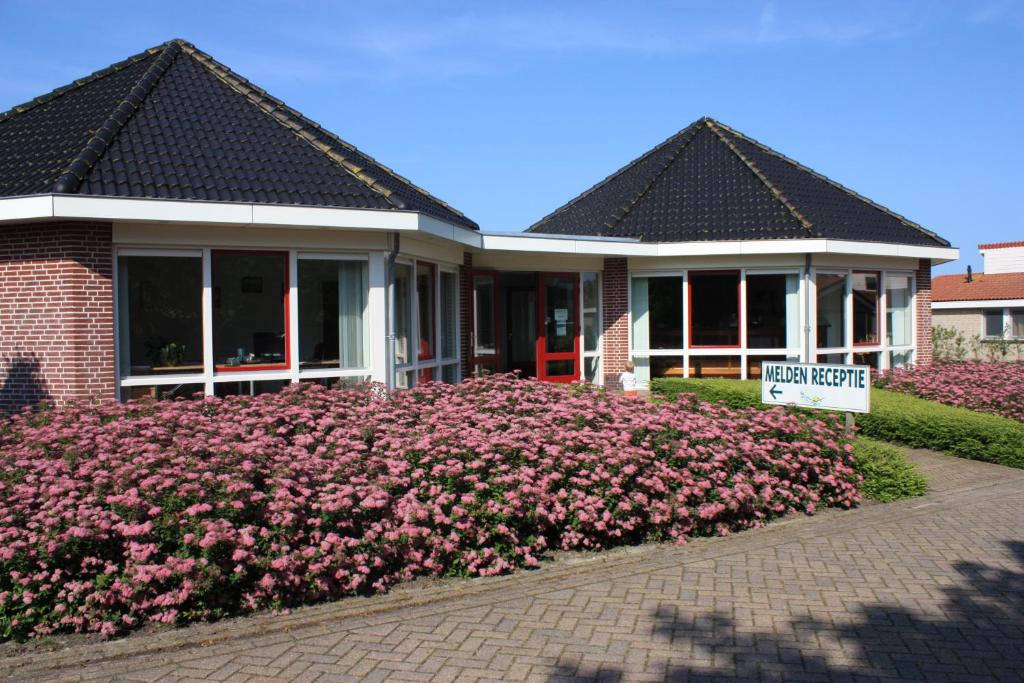 Uma casa com um ramo de flores cor-de-rosa à frente. em Vakantiepark Zijpersluis em Burgerbrug
