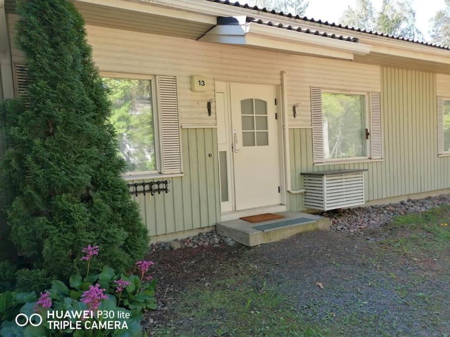 a small green house with a white door at Cozy 73m2 terraced house with sauna in Naantali