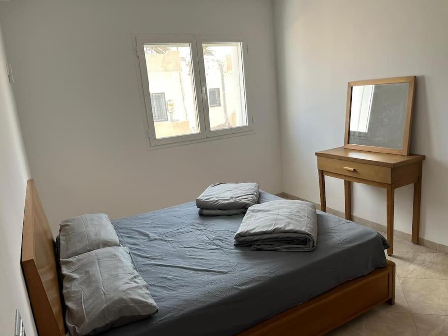 a bedroom with two beds and a dresser and a mirror at Studio Rouge Cosy à Dar Lili Djerba in Mezraya