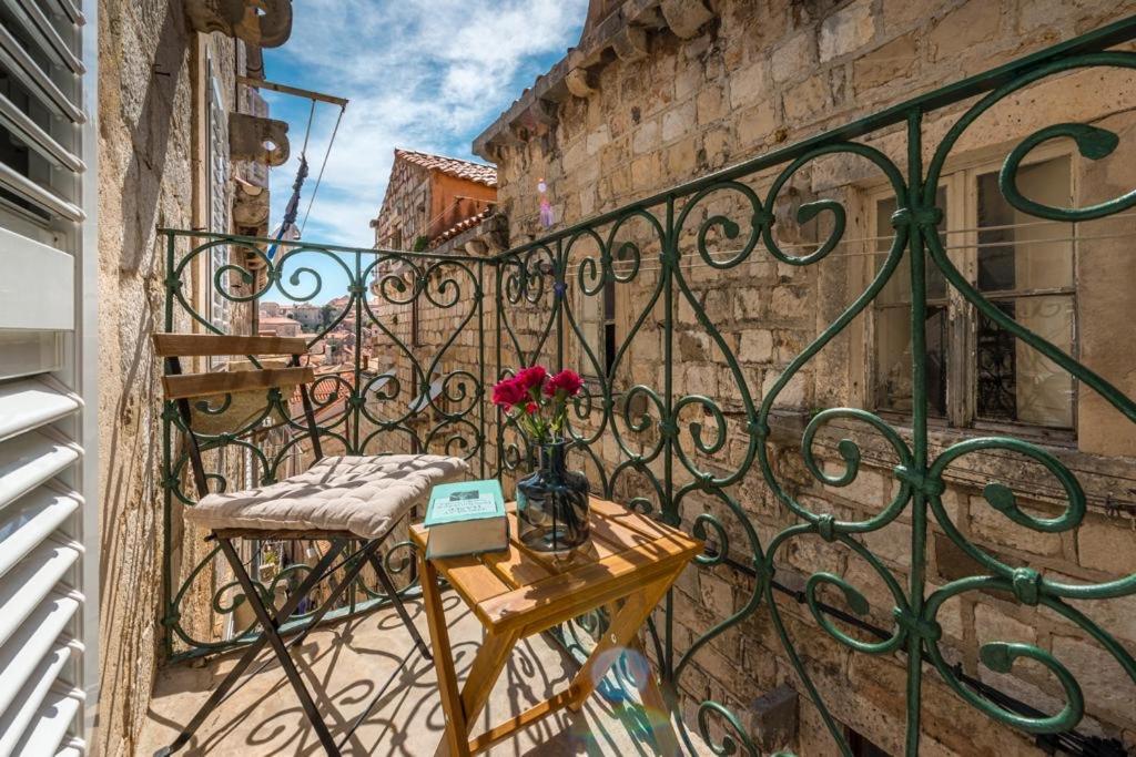 a balcony with a table with flowers on it at House Old Town Dubrovnik in Dubrovnik